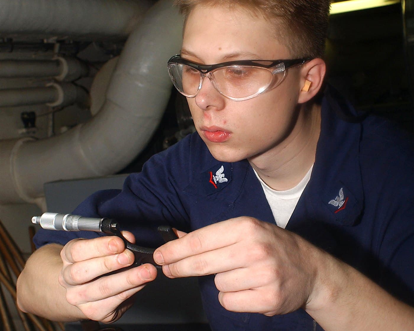 A machinist checking a machined part with a hand micrometer in a machine shop