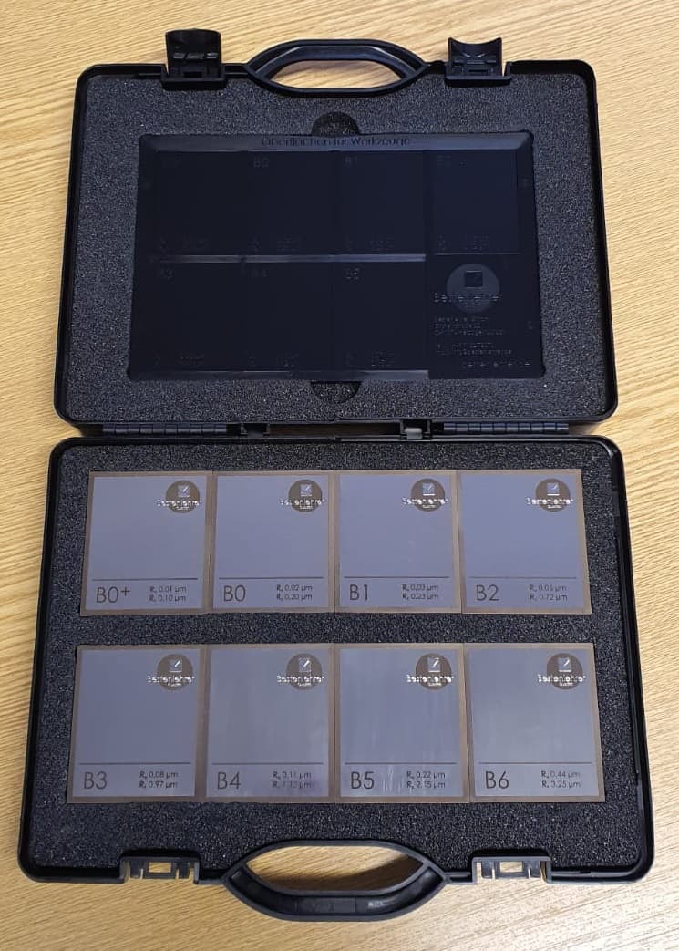 A case of eight hand polished surface roughness comparison specimens labeled B0 plus through B6, each marked with its Ra and Rz values in micrometres